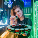 Vodka Voronskaya Bio - Woman holding a tray of drinks in a neon-lit bar setting