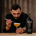 Vodka Voronskaya Black Edition - Man preparing a cocktail with a bottle of Vodka Voronskaya on a wooden surface.