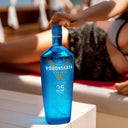 Vodka Voronskaya Blue - Blue bottle of Voronskaya vodka on a table with a blurred background of people lounging.
