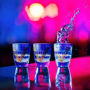 Vodka Voronskaya Classic - Three shot glasses on a reflective surface with a colorful blurred background.