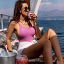 Vodka Voronskaya Classic - Woman in pink top and white skirt sitting on a boat, drinking from a glass.